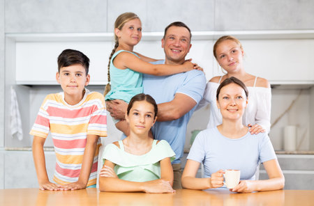 Happy family with four children sitting at table at home