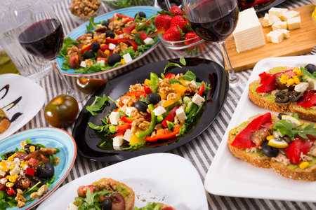Many plates with tasty vegetarian food and wine in glass