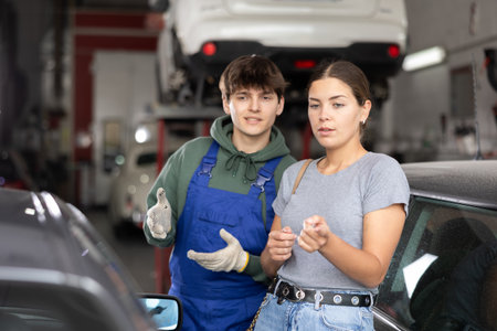 Girl who owns car talks about problems to an auto mechanic at car service centerの写真素材