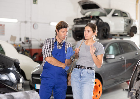 Female client talking to auto mechanic about maintenance of car