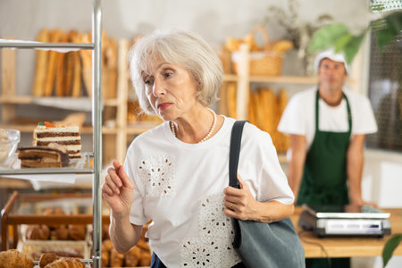 Elderly woman chooses piece of cakeの写真素材