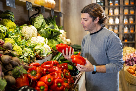 Adult man shopper chooses bell pepper in shopの写真素材