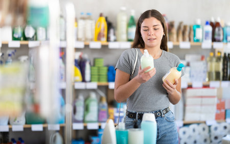 Young woman buyer chooses liquid soap in storeの写真素材