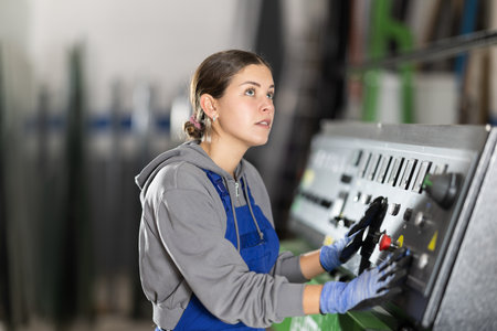 Young woman operates control panel in factoryの写真素材