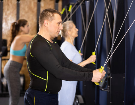Sporty male athlete using skierg machine in gym