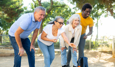 Carefree multiracial friends throwing metal balls on a sandy background in the parkの写真素材