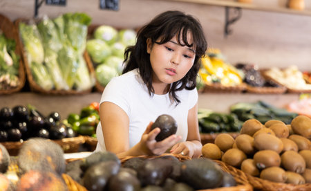 Asian girl choosing fruits in supermarket