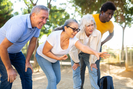 Carefree multiracial friends throwing metal balls on a sandy background in the parkの写真素材