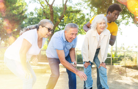 Cheerful males and females playing petanque in park on holidaysの写真素材