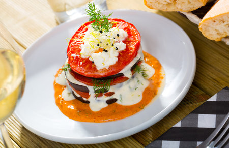 Tasty stack of fried eggplants and tomatoes on spicy sauce served at plate