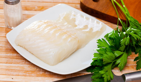 Piece of raw rockling fillet with fresh parsleyの写真素材