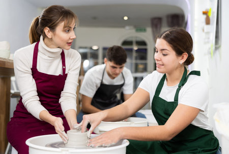 Two young women sculpt product on potters wheelの写真素材