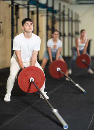 Athletic young guy pumping up his arm biceps using one side of barbellの写真素材