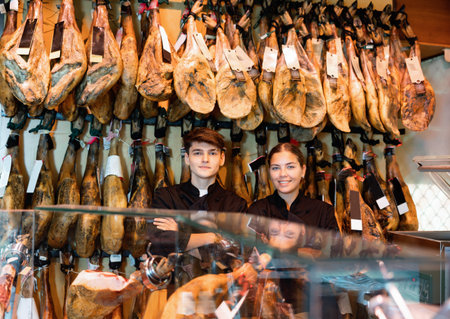 Young couple work together in butcher shop - they cut traditional Spanish jamonの写真素材