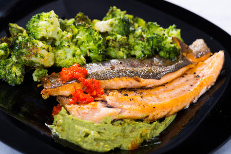 Fried trout with broccoli and saucesの写真素材