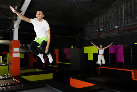 Joyful young man jumping on trampolines in colorful amusement parkの写真素材