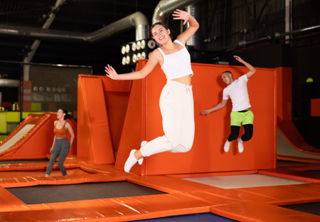 Happy girl bouncing on trampoline in indoor amusement park