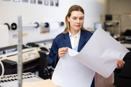 Worker checking paper in printing press workshop