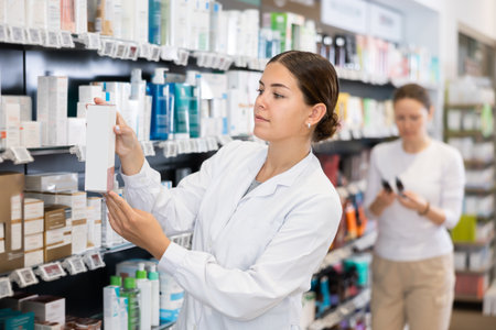 Female pharmacist puts goods on the shelves - healing cosmetics and body careの写真素材