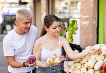 Married couple near vegetable stand in store choose daikon radishの写真素材