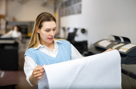 Printing establishment worker examining large piece of paper
