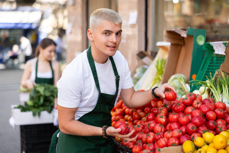 Guy shop seller puts tomatoes on display case