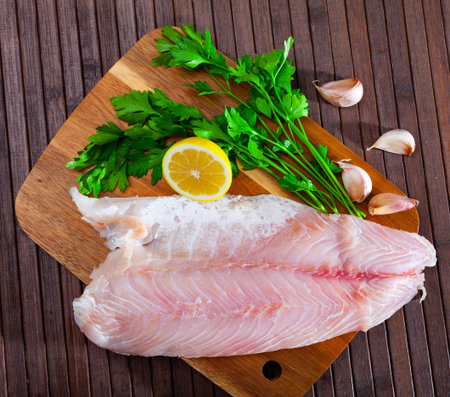 Image of fillet of raw perch fillet before cooking with greens