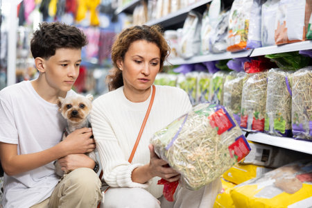 Mom and boy with dog Yorkshire Terrier, take hay from shelf, in pet store.の写真素材