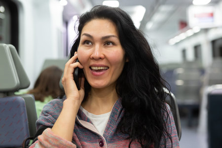 Woman traveler talking on mobile phone in subway train car