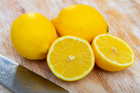 Ripe yellow whole lemons and fruit cut in half lie on wooden tableの写真素材