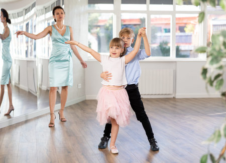 Boy and girl train to dance contemporary vigorous rumba during classes.