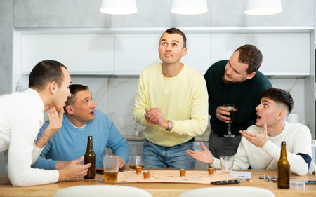 Cheerful men playing drinking board game at bachelor gathering