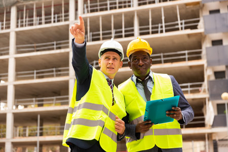 Foreman showing builder something at the construction site by pointing hand