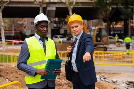 Architect tells engineer where to dig a trench to lay pipe