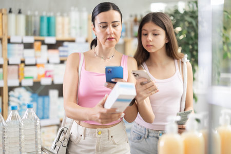 Woman and girl daughter in pharmacy scans QR code on creamの写真素材