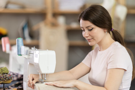 Woman seamstress sews on sewing machine in workshop
