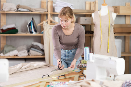 Tailor woman cutting fabric in the workshop