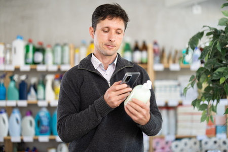 Middle-aged man scanning QR-code on detergent at supermarket