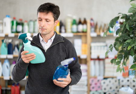 Middle-aged man choosing cleaning spray at department storeの写真素材