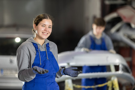 Portrait of a positive girl auto mechanic in the interior of car service