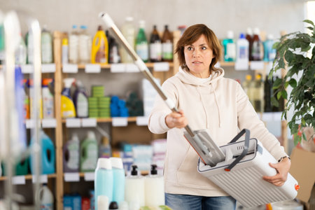Adult woman chooses mop in storeの写真素材