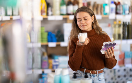 Young woman choosing scented candles in storeの写真素材