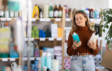 Young woman choosing shampoo or shower gel in storeの写真素材