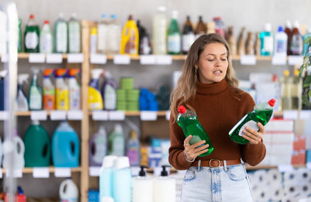 Young woman choosing dishwashing liquid in department storeの写真素材