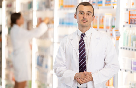 At pharmacy, man apothecary waiting for customers, invite with gesture go to department of cosmetic