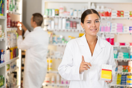 Young female pharmacist offering preparation in boxの写真素材