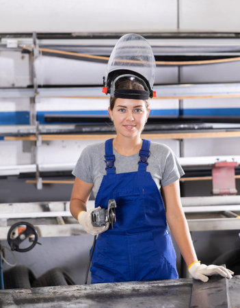 Woman cutting aluminum profile for windows using angle grinder