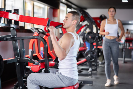 Young man trains his arms on machine