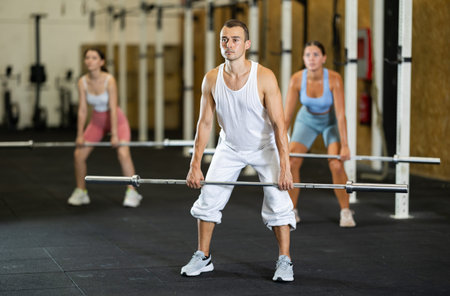 Athletic man doing squats with barbell in gym