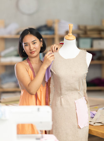 Woman seamstress adjusts clothes on mannequin